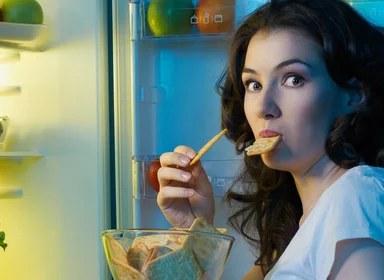 Porušení diety – žena u lednice jí sušenky